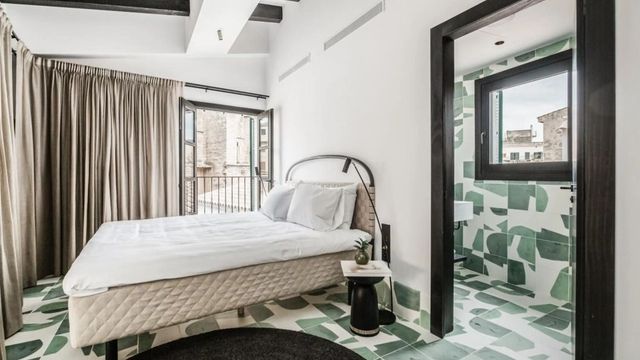 Modernes Hotelzimmer mit Balkon und grün gemustertem Bodenbelag