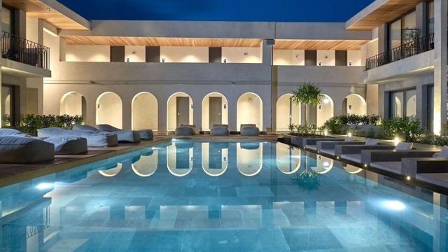 Luxuriöser Hotelpool bei Nacht mit eleganter Architektur und beleuchteten Liegen