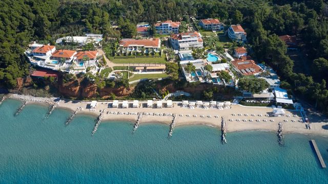 Luftaufnahme des Hotelkomplexes am Strand mit üppiger Vegetation und blauem Meer.