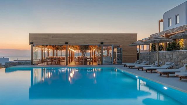 Moderner Poolbereich mit angrenzendem Restaurant bei Sonnenuntergang.