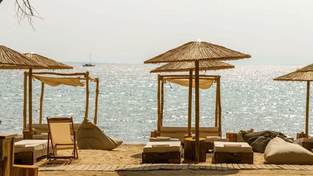Sonnenliegen unter Strohschirmen an einem Sandstrand