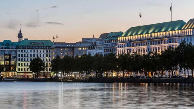 Elegante Fassade des Hotels Fairmont am Abend über der Alster in Hamburg.