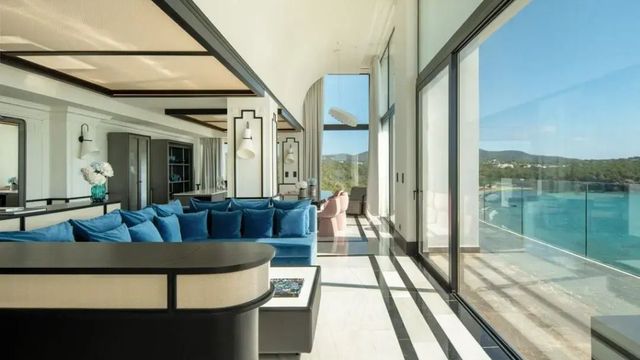 Großer Wohnbereich mit blauen Sofas und Panoramaausblick in der Suite.