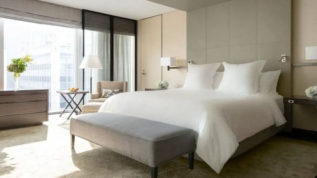 Helles und gemütliches Schlafzimmer mit weißer Bettwäsche und Sitzbereich.