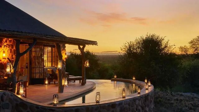 Infinity-Pool bei Sonnenuntergang mit Laternen und Blick in die Wildnis.