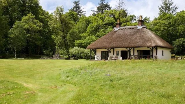 Reetgedecktes Häuschen inmitten grüner Natur mit einem gepflegten Garten.