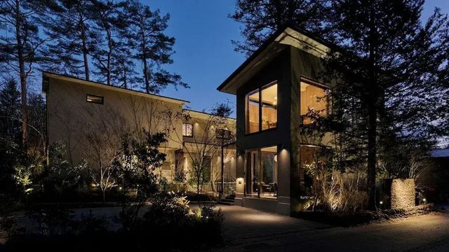 Hotelgebäude in der Abenddämmerung mit beleuchteten Fenstern und Bäumen.