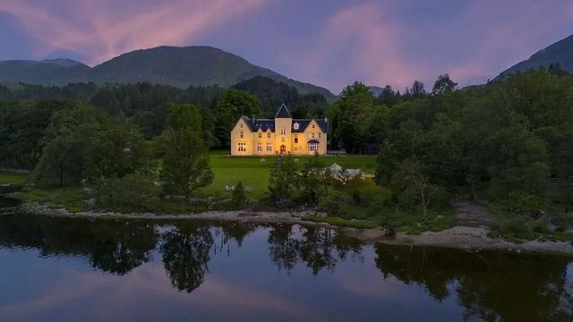 Schönes Hotelgebäude in idyllischer Landschaft am Abend mit beleuchteten Fenstern