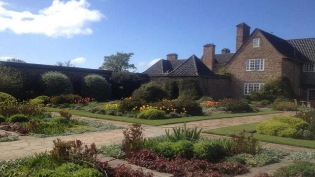 Große Gartenanlage des Hotels mit gepflegten Blumenbeeten und historischem Charme