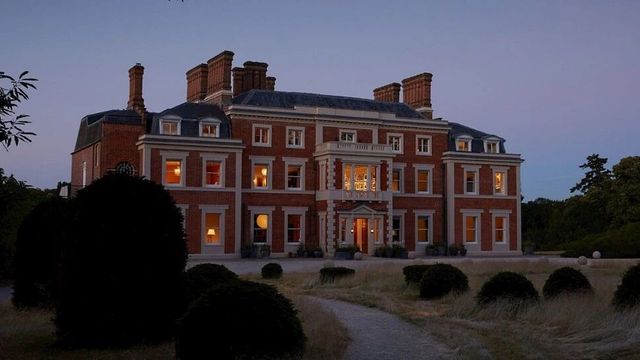 Historisches Gebäude von Heckfield Place in der Dämmerung mit erleuchteten Fenstern