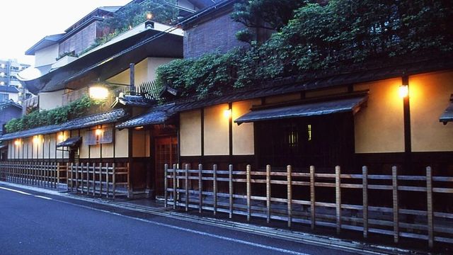 Traditionelle japanische Ryokan-Fassade mit Holzdetails und Pflanzenbeleuchtung.