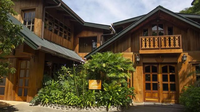 Holzfassade des Hotels mit üppiger Vegetation im Eingangsbereich