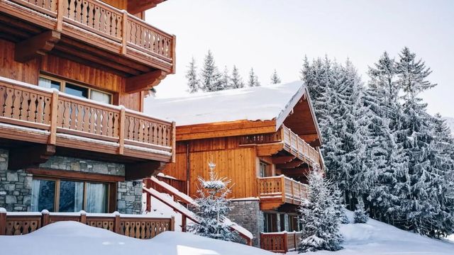 Verschneite Holzhütten des Hotel Le Coucou Méribel in alpiner Landschaft