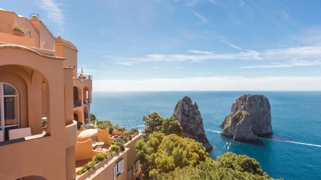 Hotelgebäude mit Meerblick und Felsenlandschaft bei sonnigem Himmel