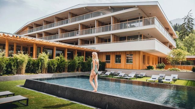 Frau am Infinity-Pool mit Blick auf Hotel