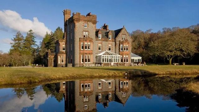 Historische Fassade des Isle of Eriska Hotels mit Spiegelung im ruhigen See