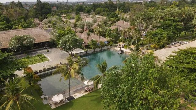 Panoramablick auf die Hotelanlage mit tropischem Garten und Pool.