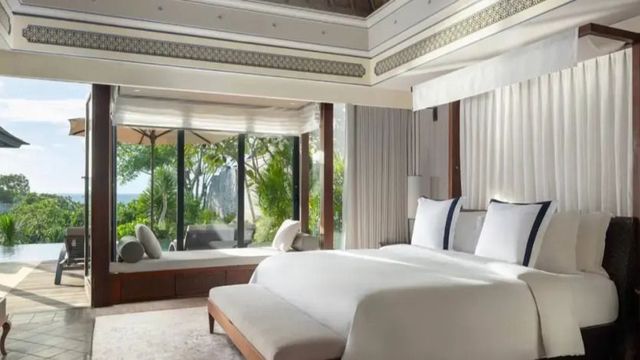 Luxuriöses Schlafzimmer mit großen Fenstern und Blick auf exotische Vegetation