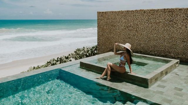 Frau im Bikini am Infinity-Pool, Strandaussicht