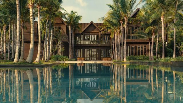 Luxuriöse Hotelvilla mit Palmen am Rand eines großen Pools.