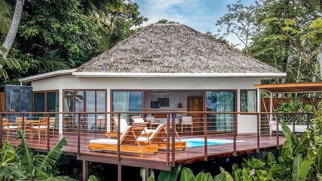 Luxuriöse Suite mit Balkon im Dschungel umgeben von üppiger Vegetation.