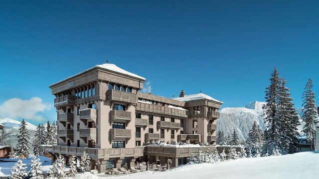 Schneebedecktes Luxushotelgebäude in den Alpen vor klarem blauen Himmel