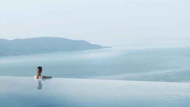 Frau entspannt im Infinity Pool mit Blick auf den Gardasee und umliegende Berge