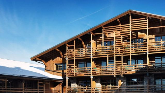 Holzfassade des Hotels Le M de Megève vor klarem blauen Himmel