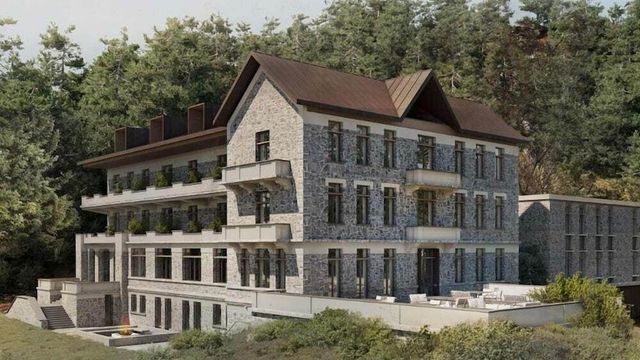 Historische steinerne Fassade des Hotels umgeben von Bäumen