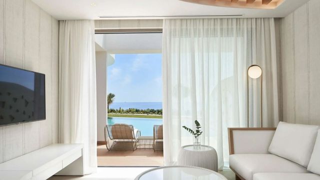 Panoramafenster mit Blick auf Pool und Meer, stilvoller Lounge-Bereich