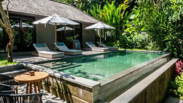 Privater Pool mit Sonnenschirmen und tropischer Umgebung.