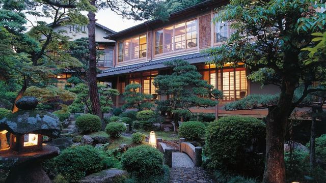 Traditionelles japanisches Hotel mit Garten und beleuchteten Laternen in der Dämmerung