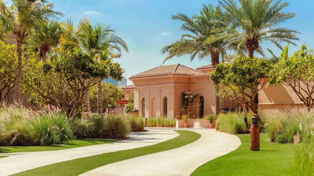 Gepflegte Gartenlandschaft mit eleganten Palmen und klassischer Architektur.