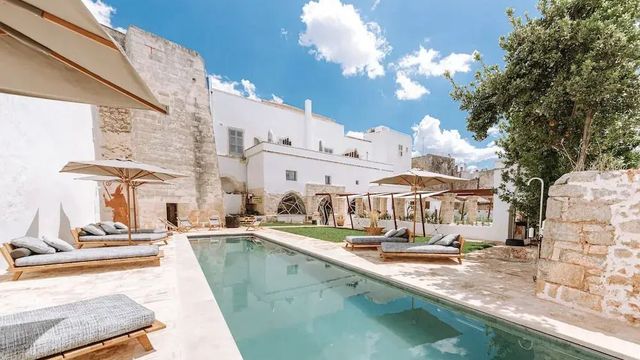 Langer, schmaler Pool mit Sonnenliegen im Innenhof des Paragon 700 Boutique Hotels.