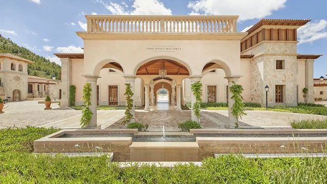 Elegante Hotelarchitektur mit Säulen und üppigem Grün im Cap Vermell Grand Hotel