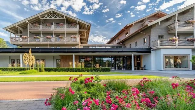 Elegante Hotelfassade mit blühendem Garten und strahlend blauem Himmel.