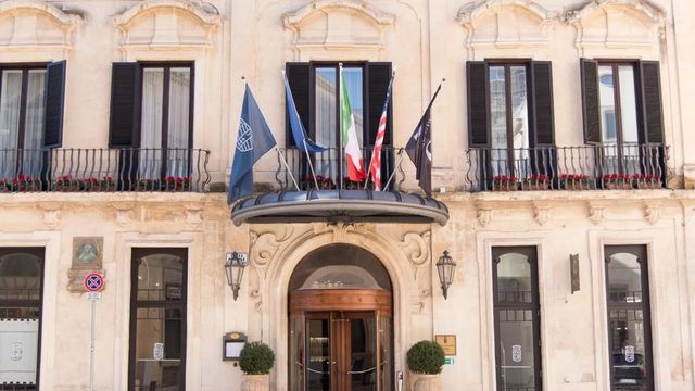 Elegante historische Fassade des Patria Palace Hotel Lecce mit Flaggen und Eingang.