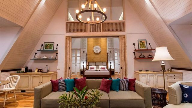 Luxuriöse Suite mit hoher Decke und gemütlichem Sofa, Holzelemente sorgen für Wärme.