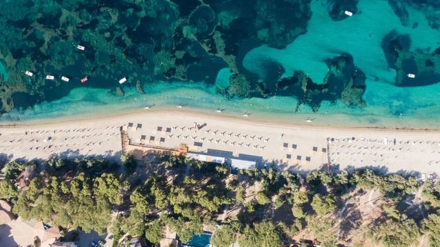Luftaufnahme des Strandes mit kristallklarem Wasser und Sonnenschirmen