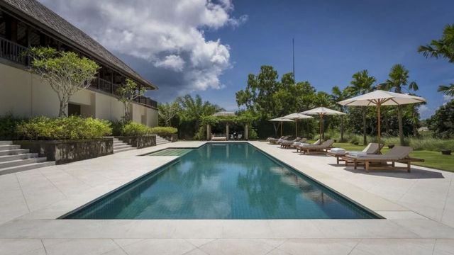 Großer Außenpool mit Liegestühlen und Sonnenschirmen unter blauem Himmel