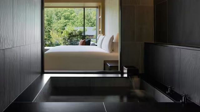 Elegante Badezimmeransicht mit Blick ins Schlafzimmer durch Fenster.