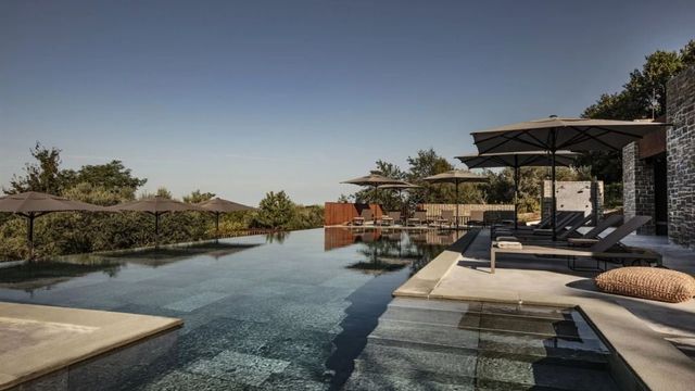 Infinity Pool mit Sonnenschirmen und Aussicht auf die umliegende Landschaft