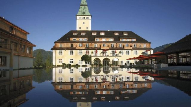 Historische Schlossfassade von Hotel Schloss Elmau spiegelt sich im Wasserbecken.