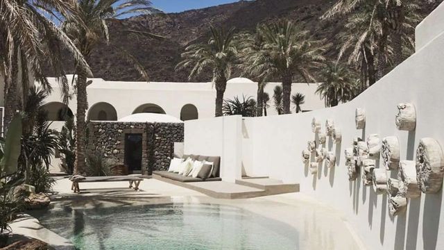 Ruhiger Poolbereich umgeben von Palmen und weißer Architektur