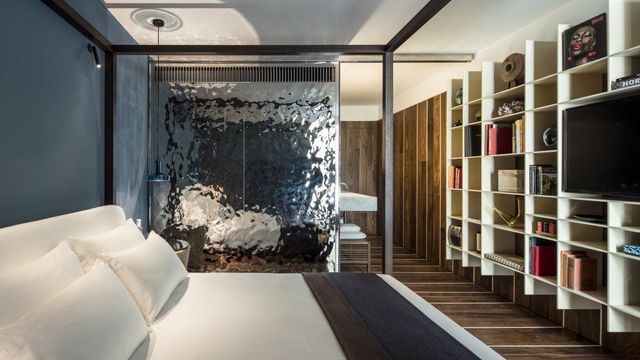 Sir Joan Zimmer im weiß-schwarzen Ambiente,, Kingsize Bett, TV und modernen Regalen