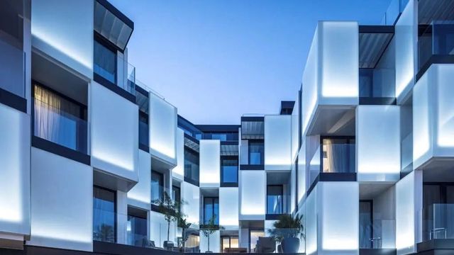 Moderne Hotelfassade mit beleuchteten geometrischen Balkonen bei Abenddämmerung