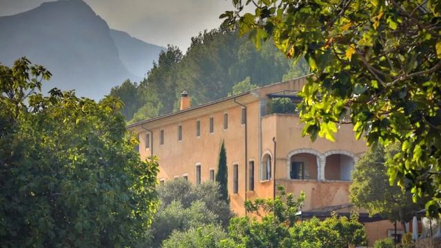 Historische Fassade von Son Brull Hotel umgeben von üppiger Natur und Bergen