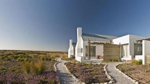 Weißes Hotelgebäude mit Heidelandschaft unter blauem Himmel
