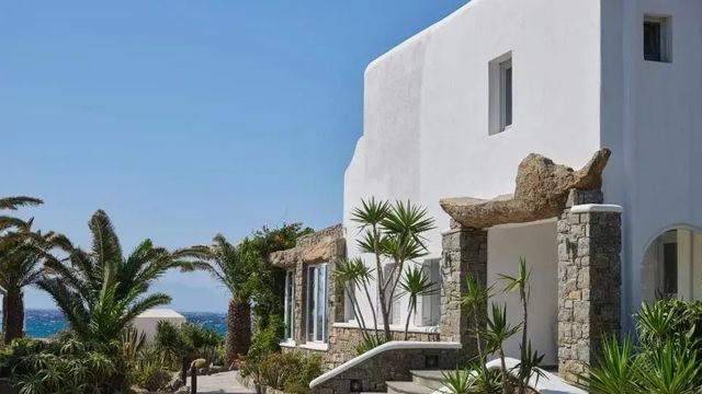 Außenansicht des Hotels mit mediterraner Architektur und Palmen im Garten