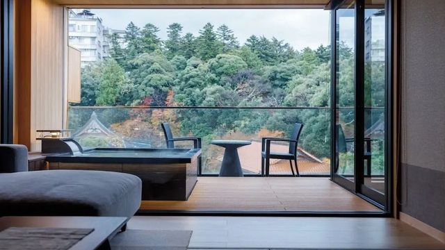 Offener Blick von Zimmer auf Balkon mit Sitzgelegenheit und grünem Ausblick